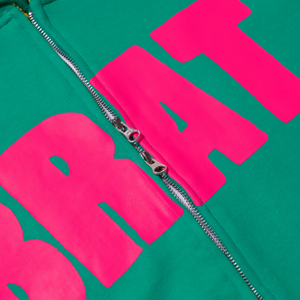 Detail perspective of Green Hoodie with pink logo reading BRAT showing dual zipper