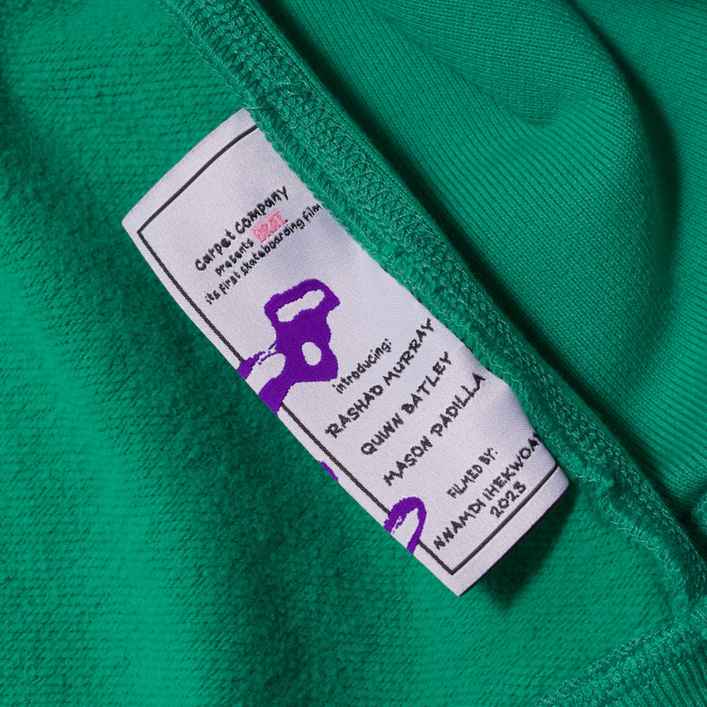 Wash tag for a green hoodie which details information about the film BRAT