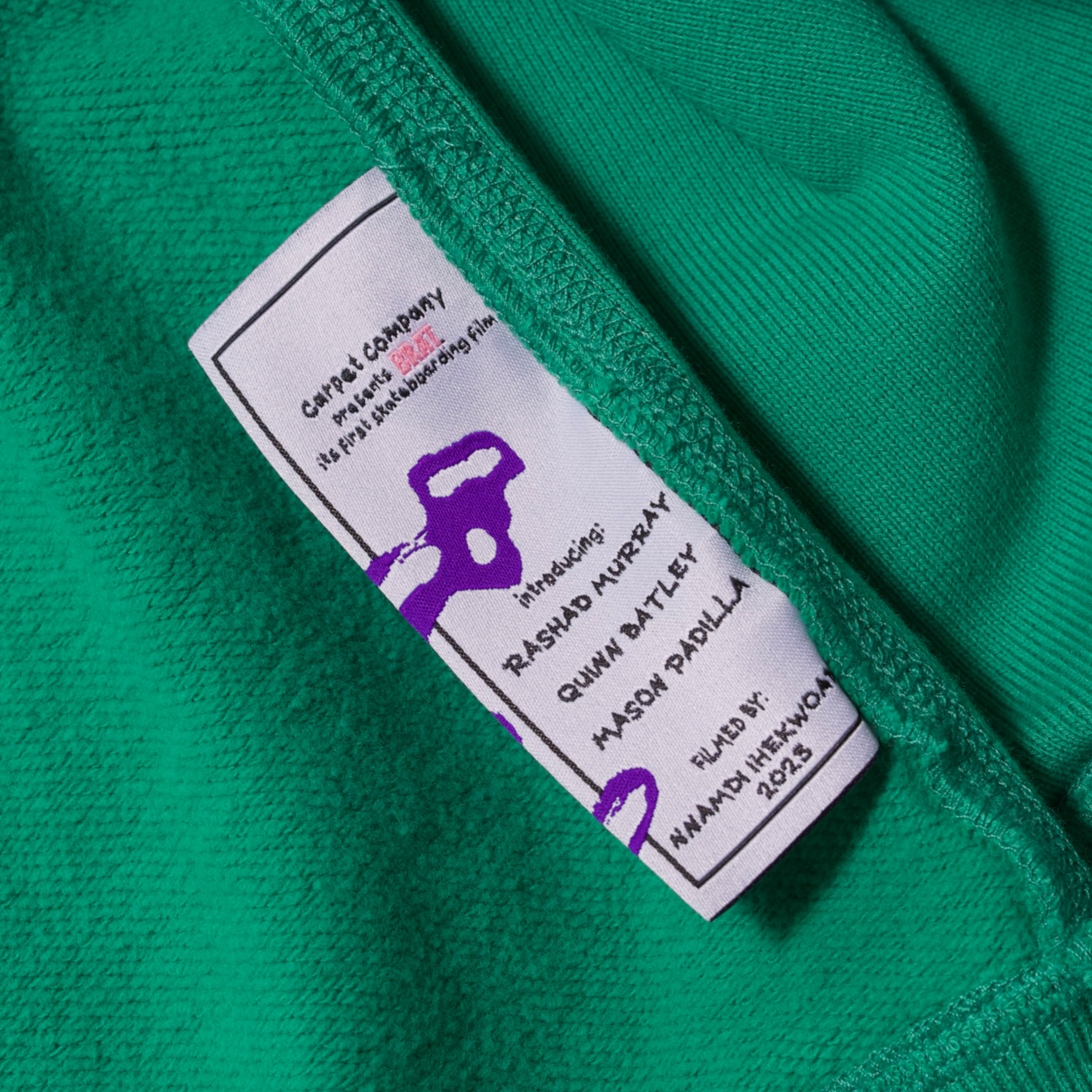 Wash tag for a green hoodie which details information about the film BRAT